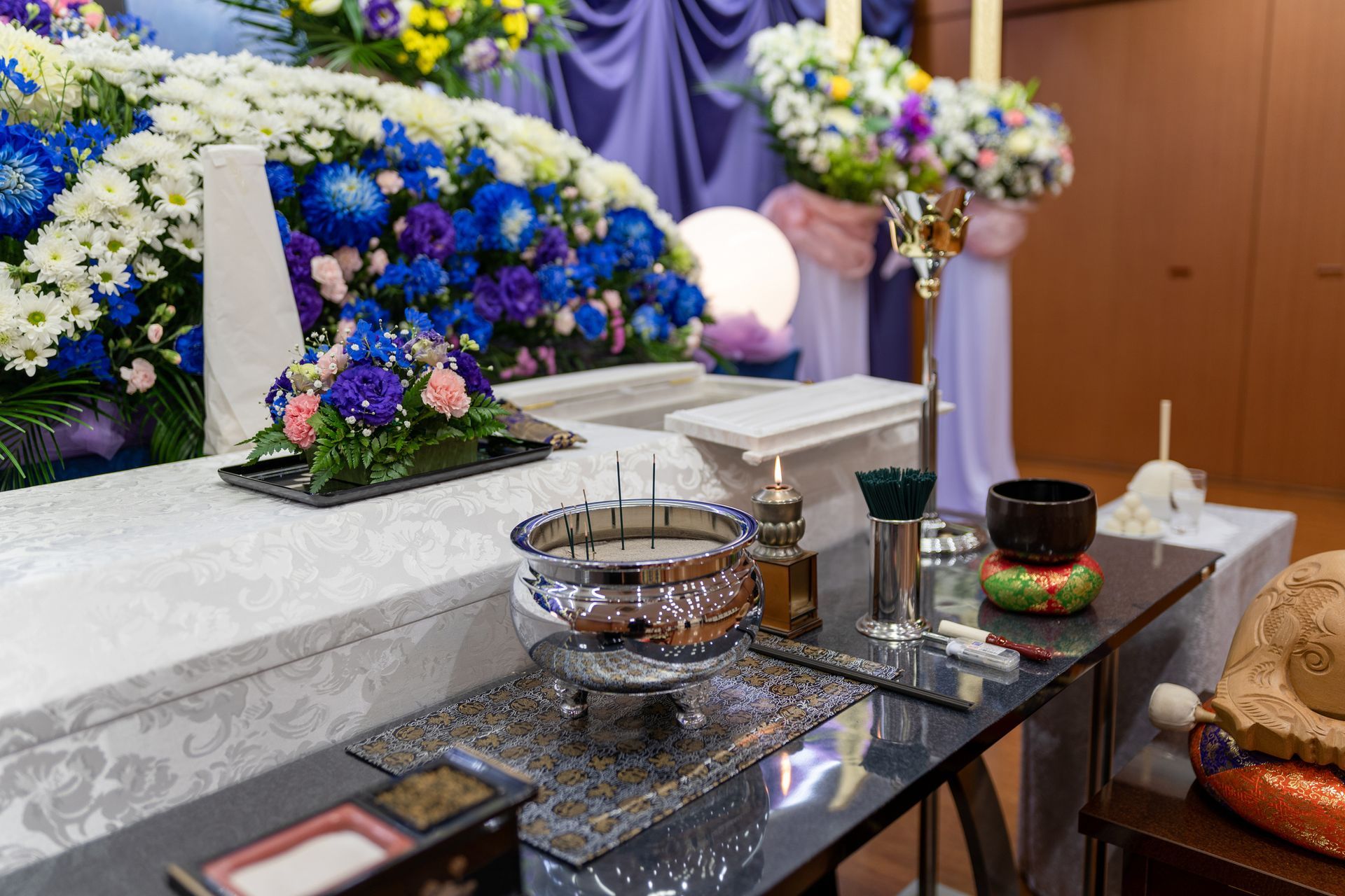 A table with candles and flowers on it in front of a coffin.