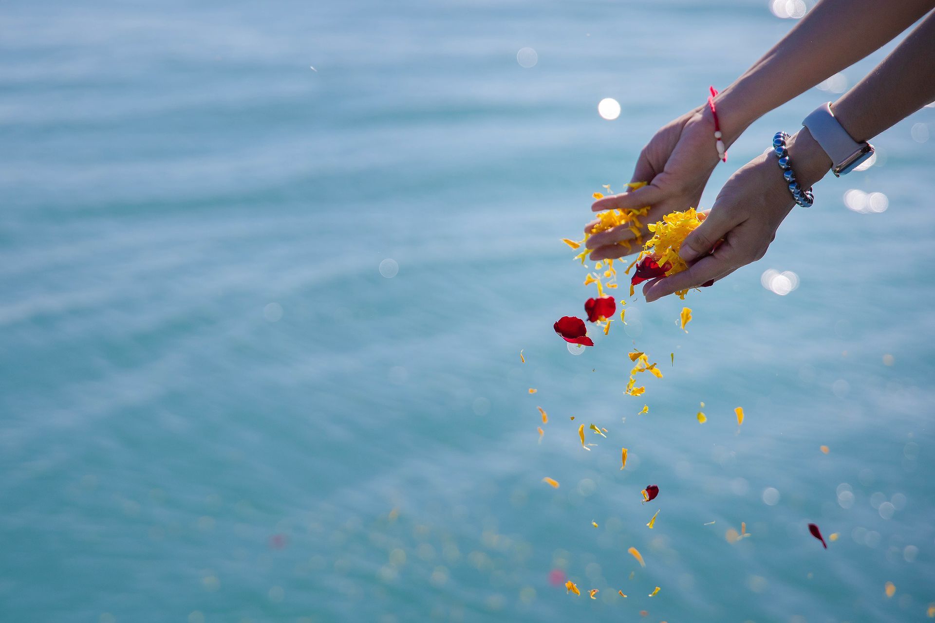 A woman is throwing flowers into the ocean.