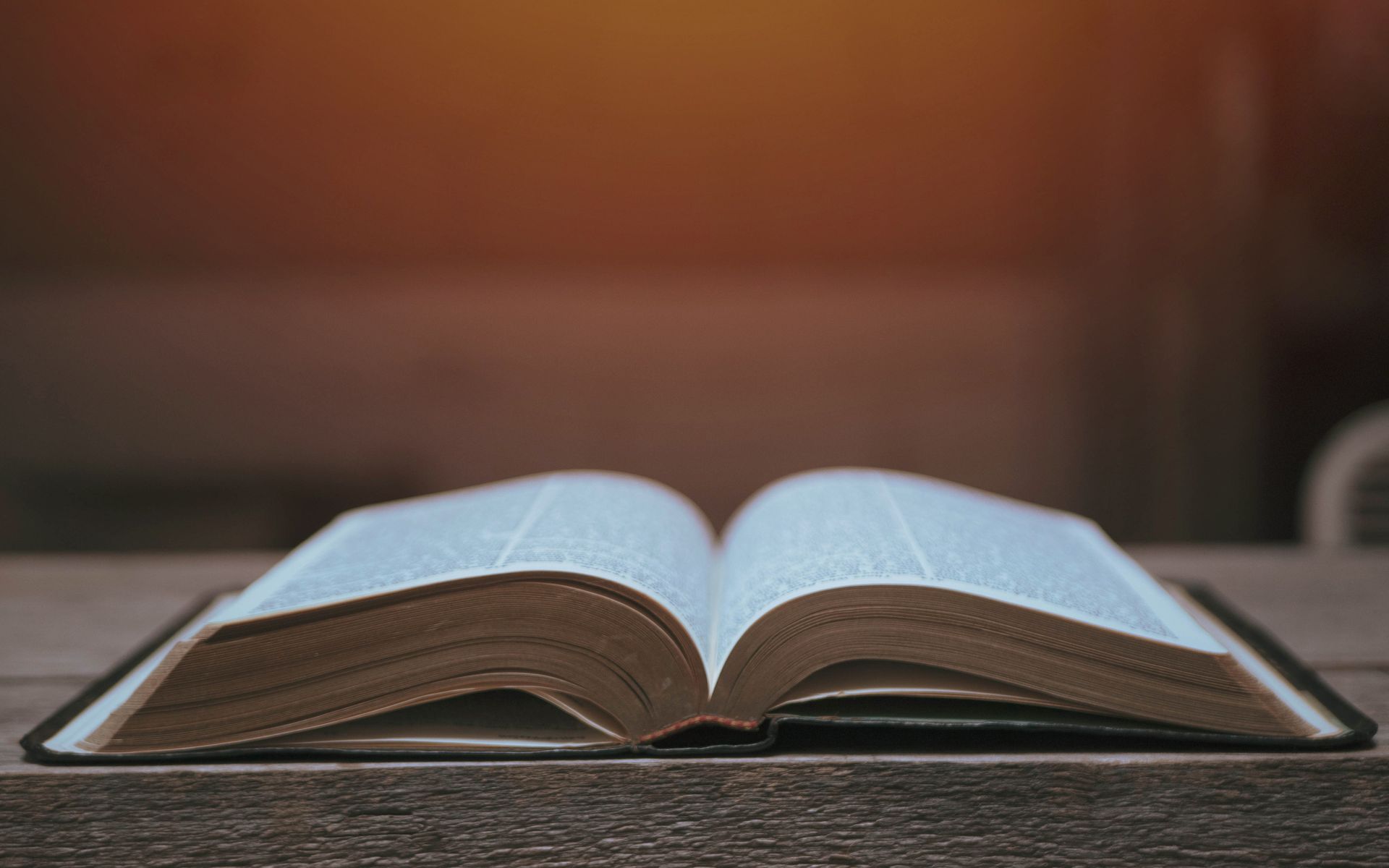 An open bible is sitting on a wooden table.