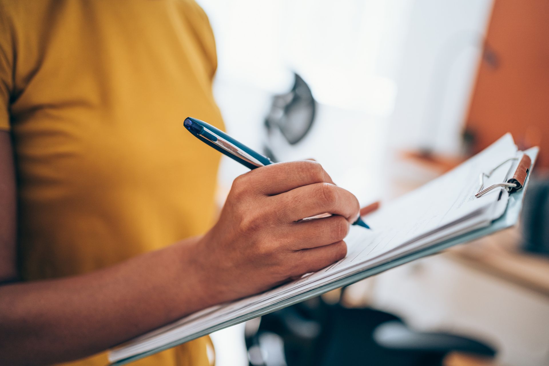 A person is writing on a piece of paper with a pen.