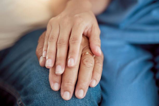 A close up of a person holding another person 's hand.