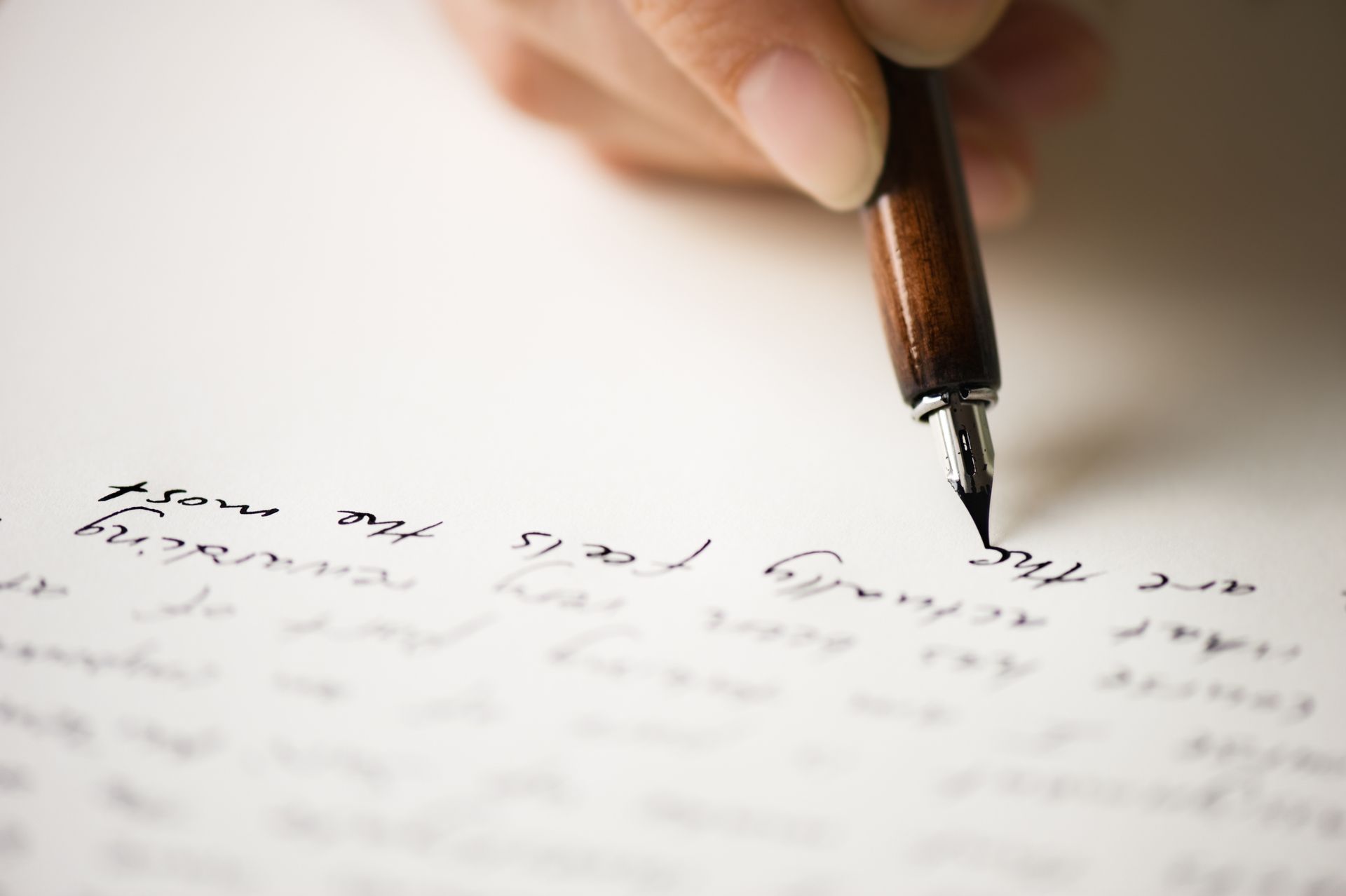A person is writing with a fountain pen on a piece of paper.