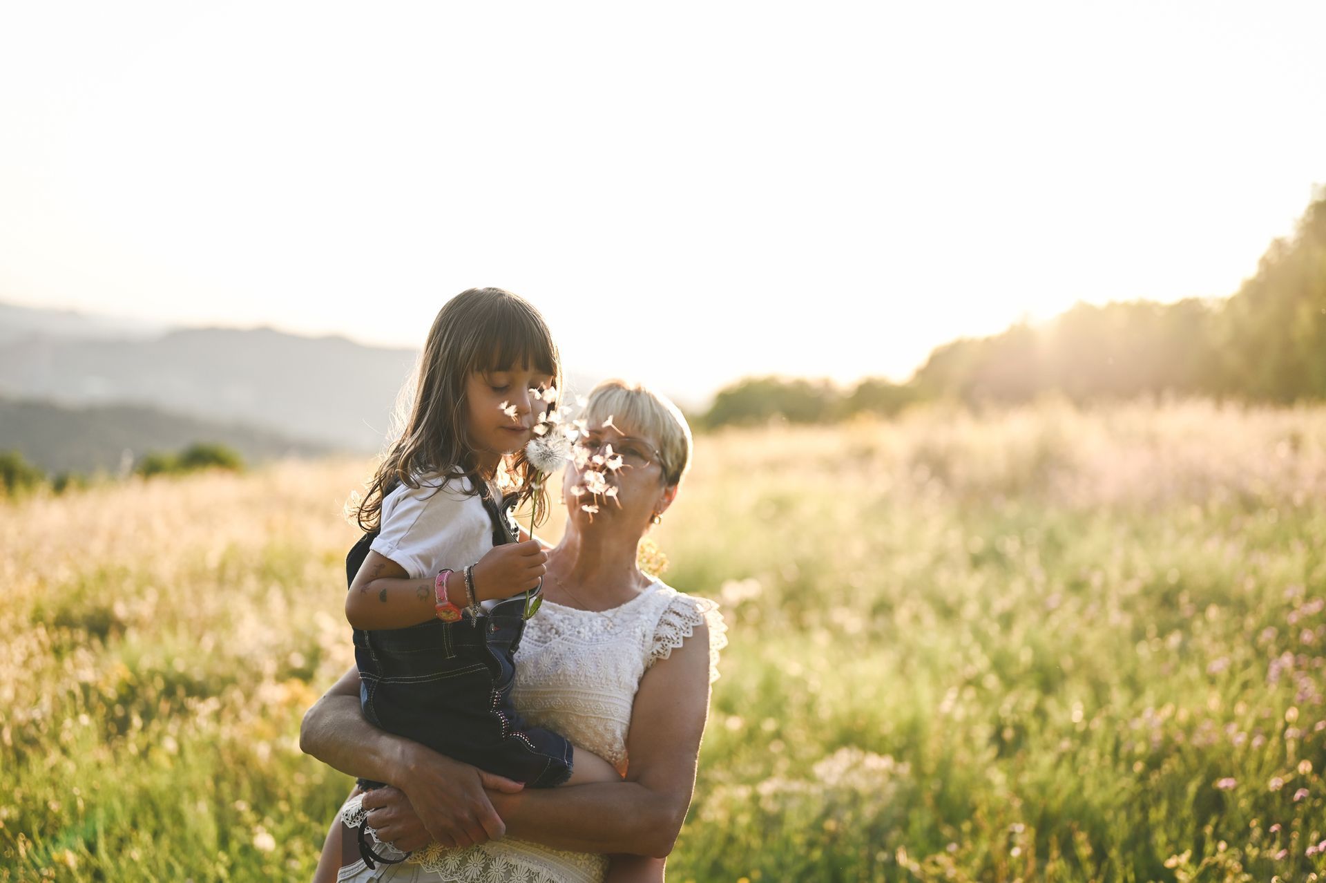 A woman is holding a little girl in her arms in a field.
