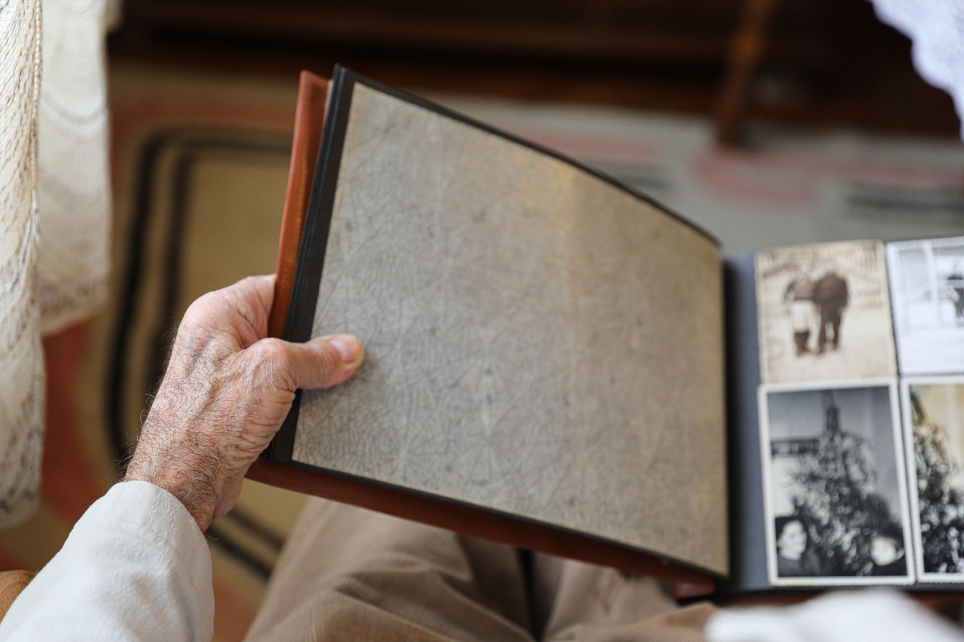 An elderly man is looking at a photo album.