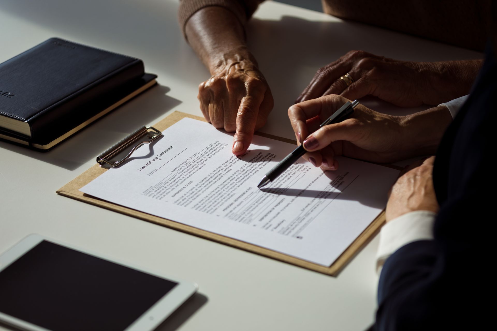 A person is signing a document on a clipboard with a pen.