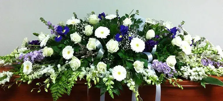 A coffin is decorated with white and purple flowers