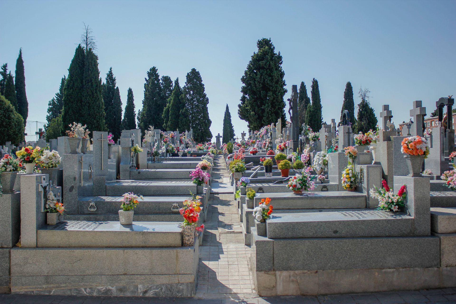 A cemetery filled with graves and flowers on a sunny day.