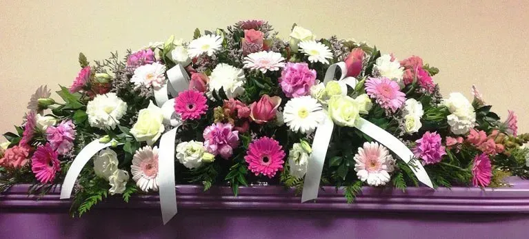 A purple coffin with pink and white flowers on it