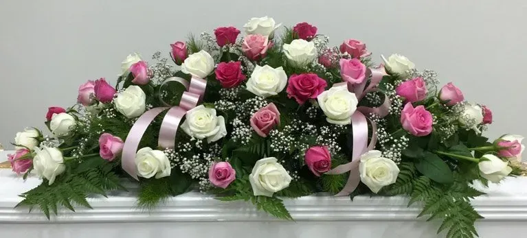 A bunch of pink and white roses are sitting on top of a white mantle.