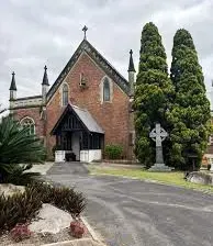 A large brick church with a cross in front of it.