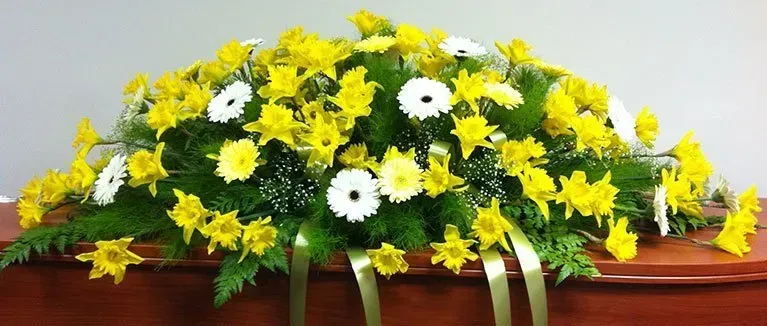 A coffin with yellow and white flowers on it