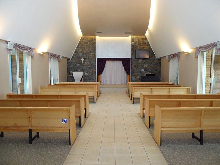 The inside of a church with wooden benches and a stone wall.