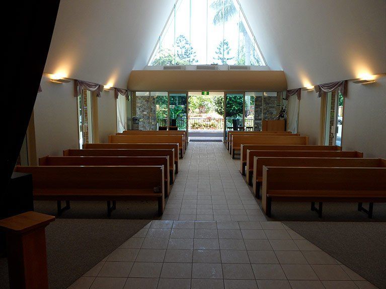 A church with rows of wooden benches and a large window.