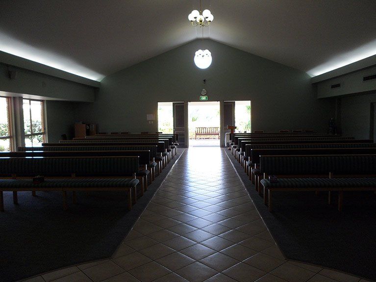 An empty church with rows of benches and a tiled floor