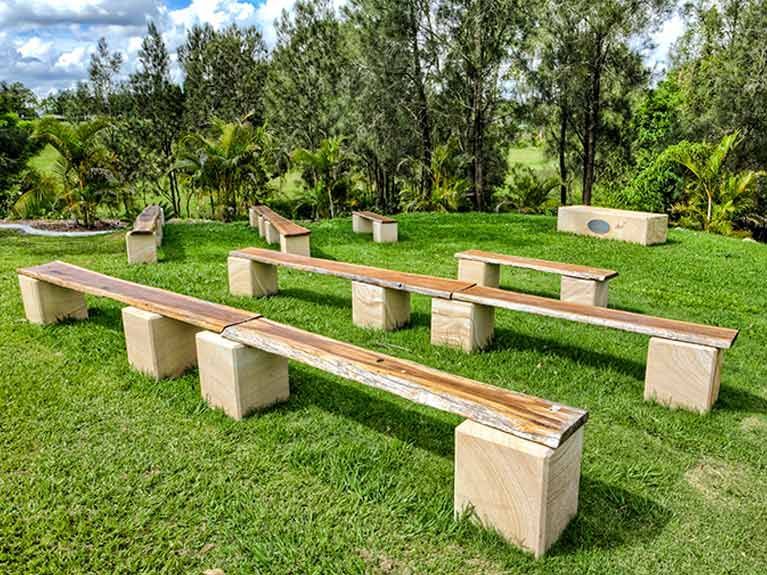 A row of wooden benches sitting on top of concrete blocks in a grassy field.