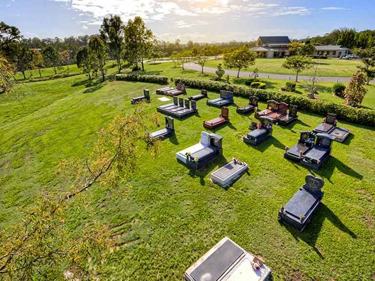 An aerial view of a cemetery with lots of graves in the grass.