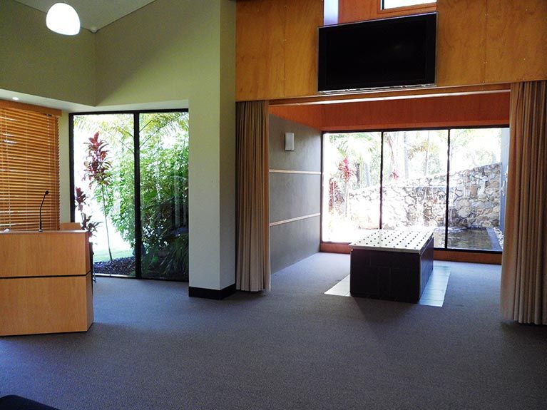 A large room with a table and a television on the wall.