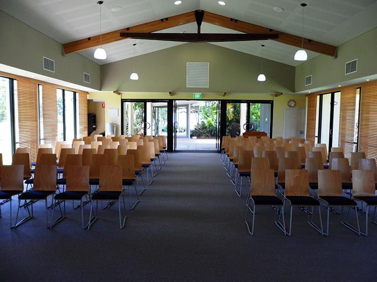 Rows of wooden chairs in a large room with a vaulted ceiling
