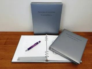 Two binders and a pen on a wooden table