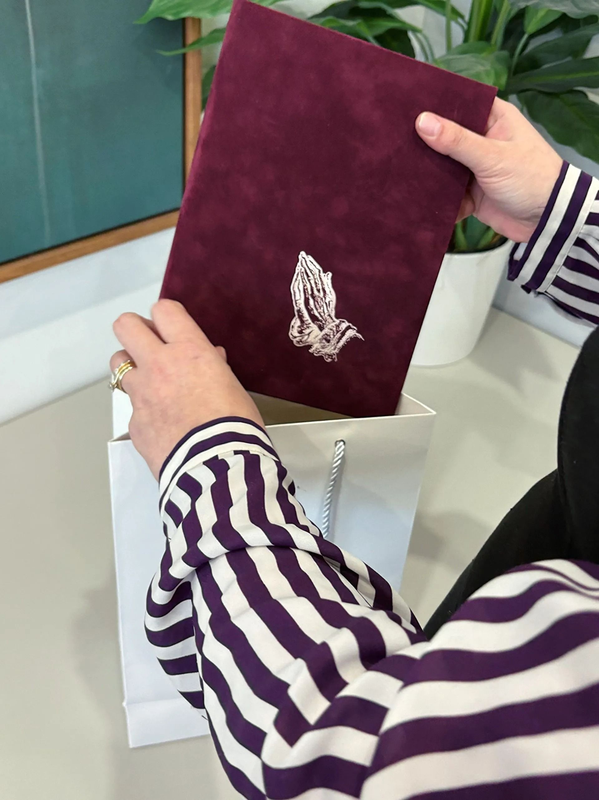A woman in a striped shirt is holding a purple book