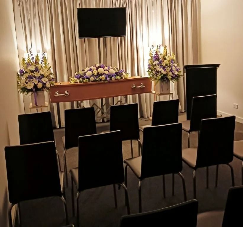 A room with chairs and a coffin with flowers on it