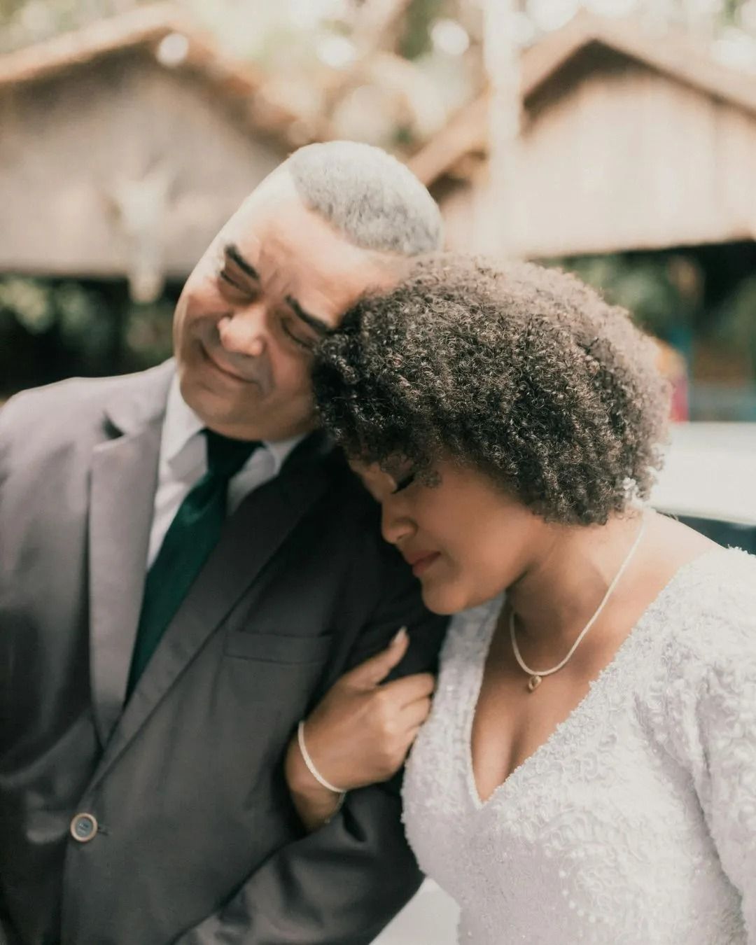 A man in a suit and tie is hugging a woman in a white dress
