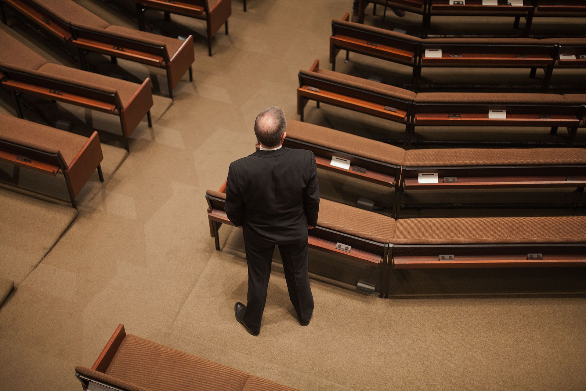 A man in a suit is standing in an empty church.