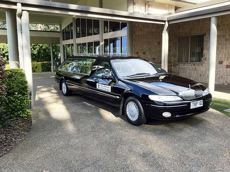 A black car is parked in front of a building.