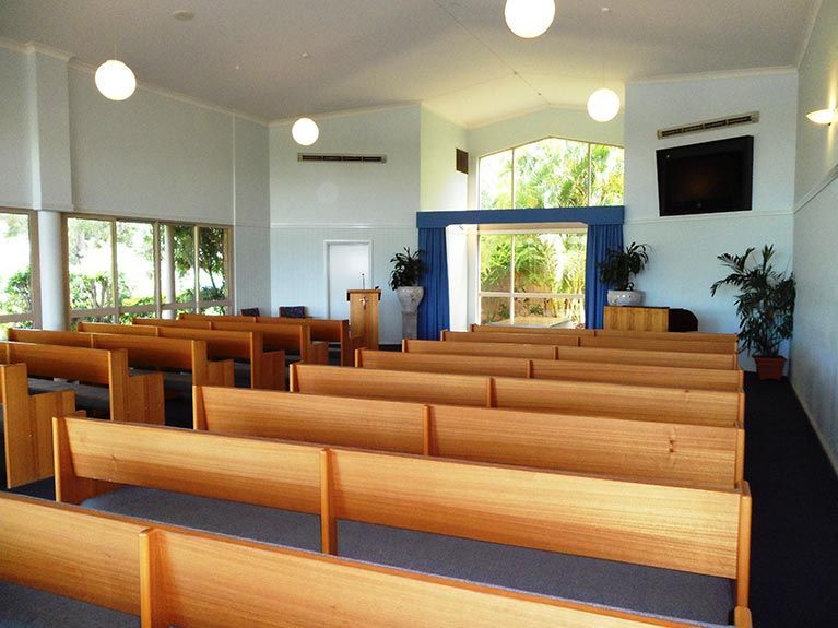 A church with rows of wooden benches and a podium
