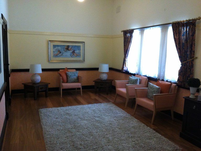 A living room with chairs lamps and a picture on the wall