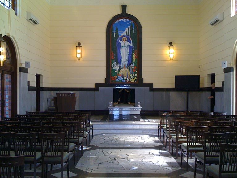 A church with rows of chairs and a painting on the wall