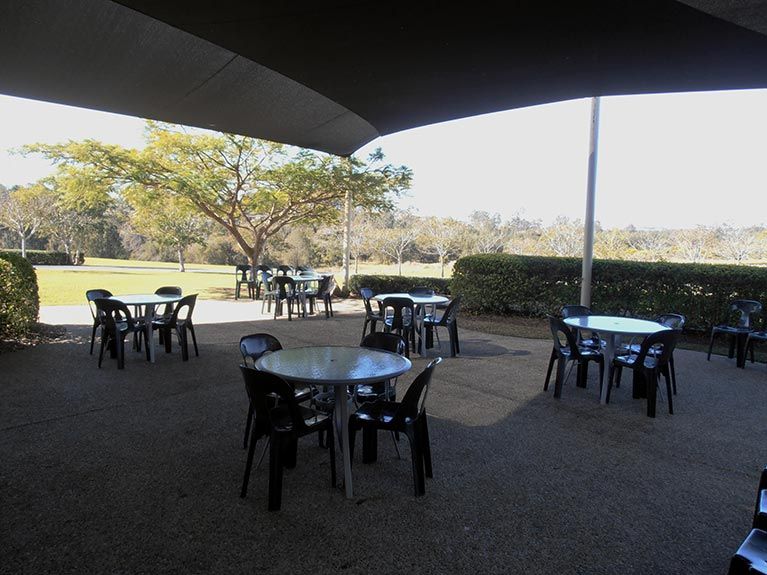 A patio with tables and chairs under an umbrella