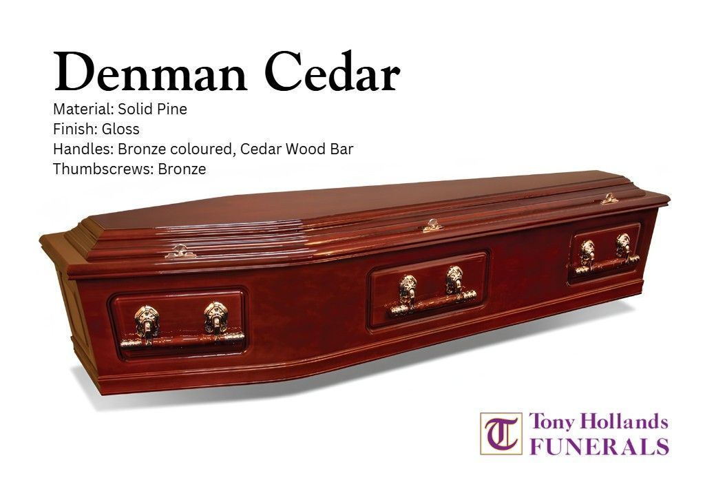 A red coffin with gold handles and a denman cedar finish is on a white background.