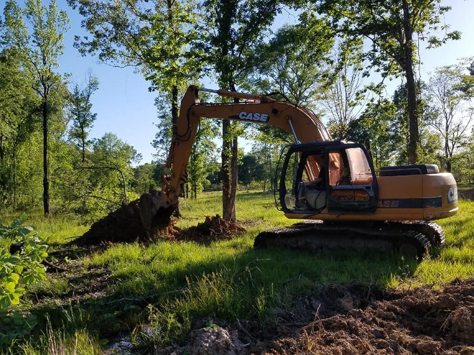 A case excavator is digging a hole in a field