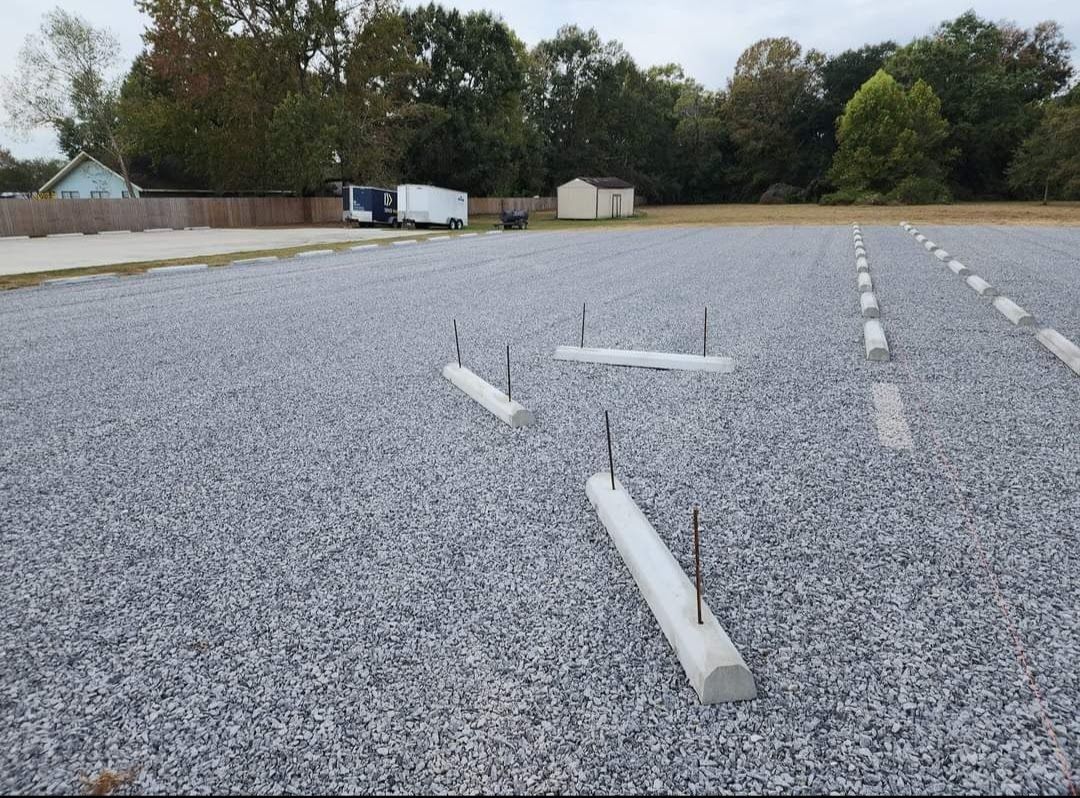 A gravel parking lot with a few white pipes in it