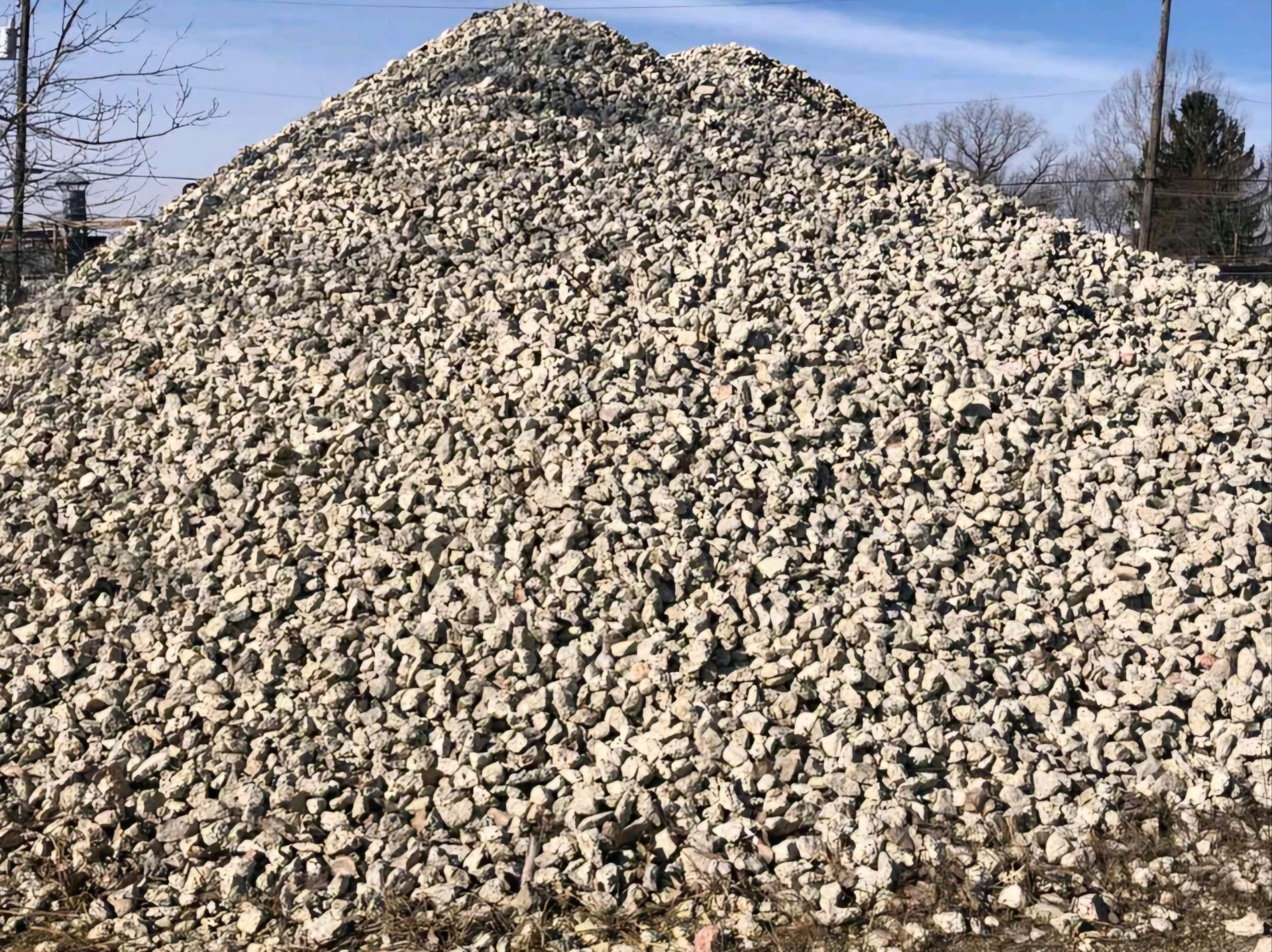 A large pile of gravel is sitting on top of a dirt field.