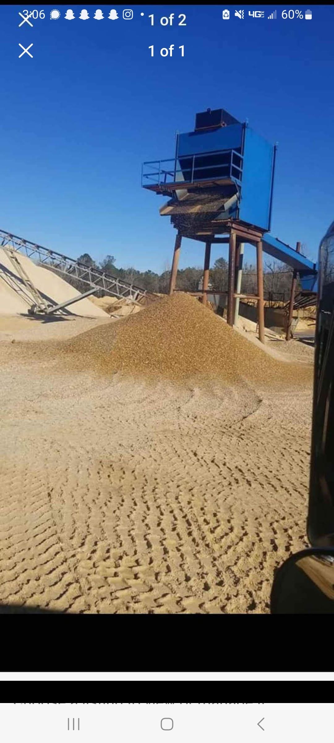 A large pile of sand is sitting in the middle of a dirt field.