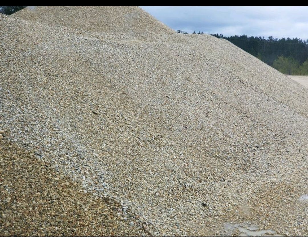 A large pile of gravel is sitting on top of a dirt field.