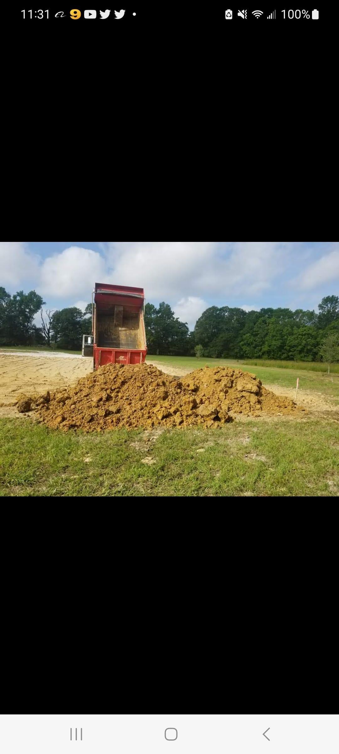 A large pile of dirt is being dumped into a field.