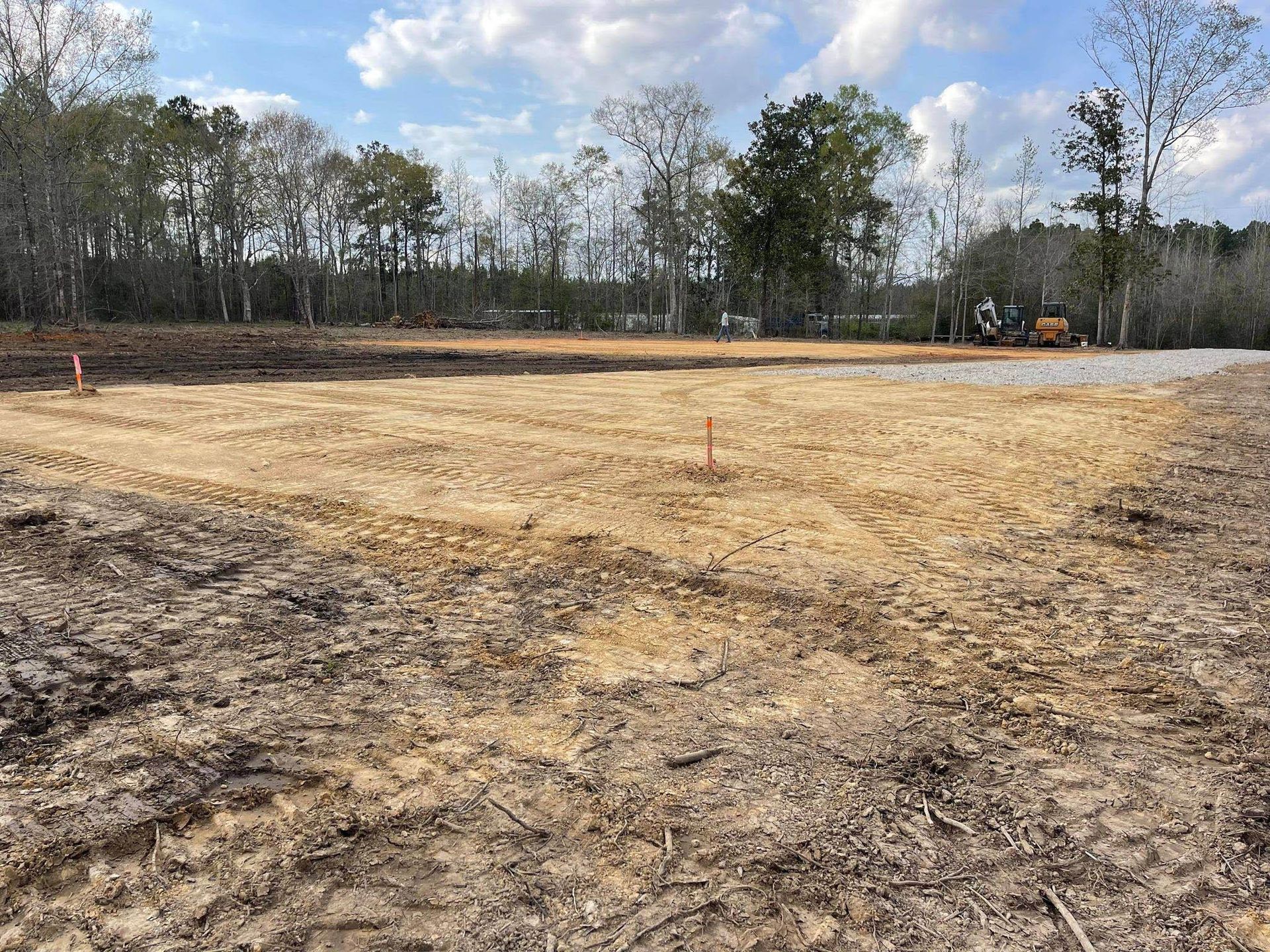 A large dry field with trees in the background and a bulldozer in the foreground.