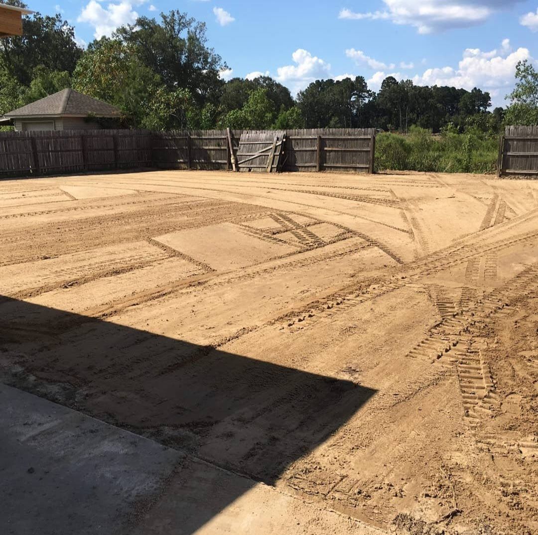 A dirt field with a wooden fence in the background