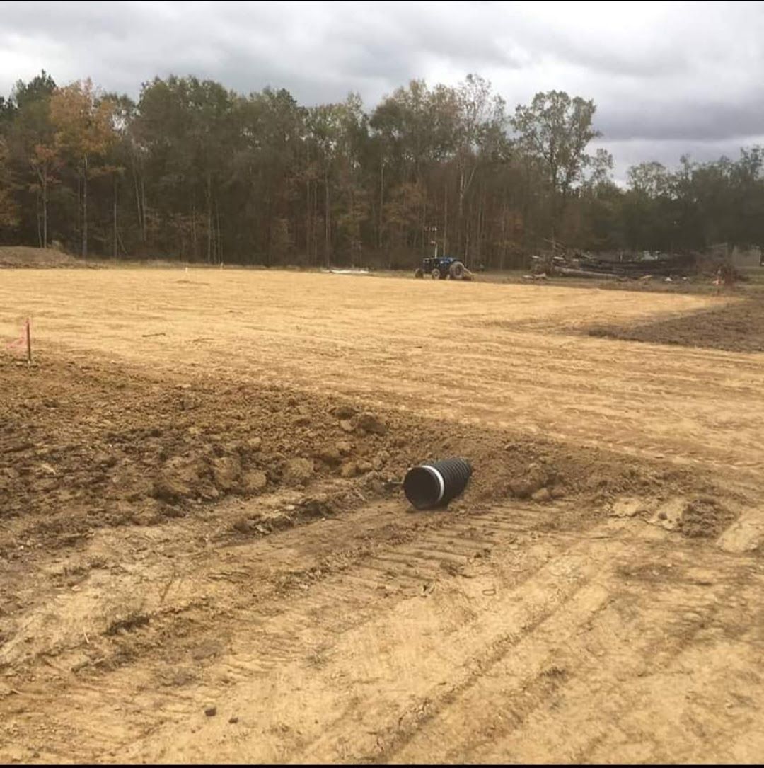 A large dirt field with a black pipe in the middle of it.