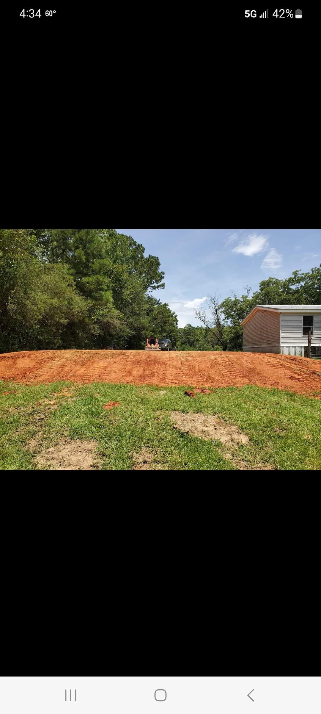 A large pile of dirt is sitting in the middle of a grassy field.