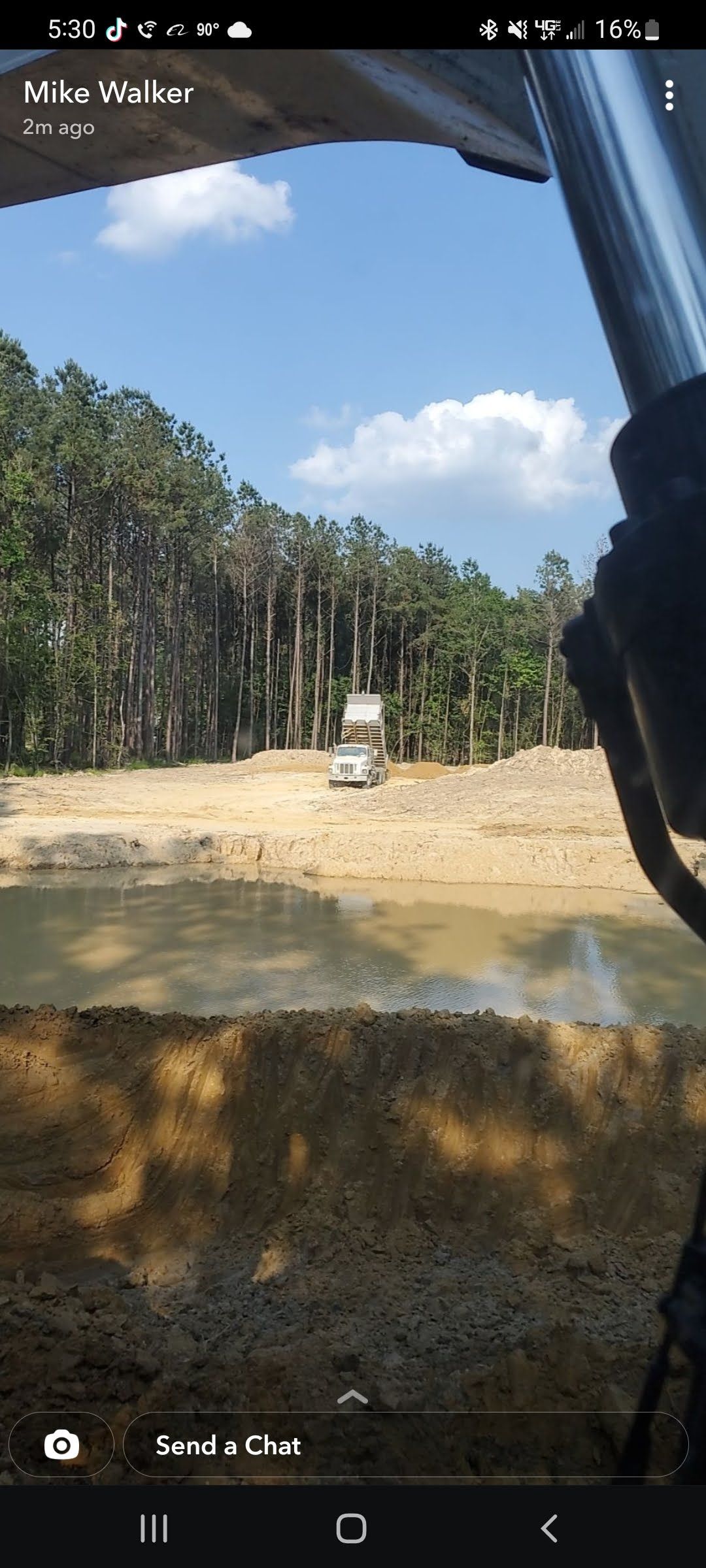 A car is driving down a dirt road next to a body of water.