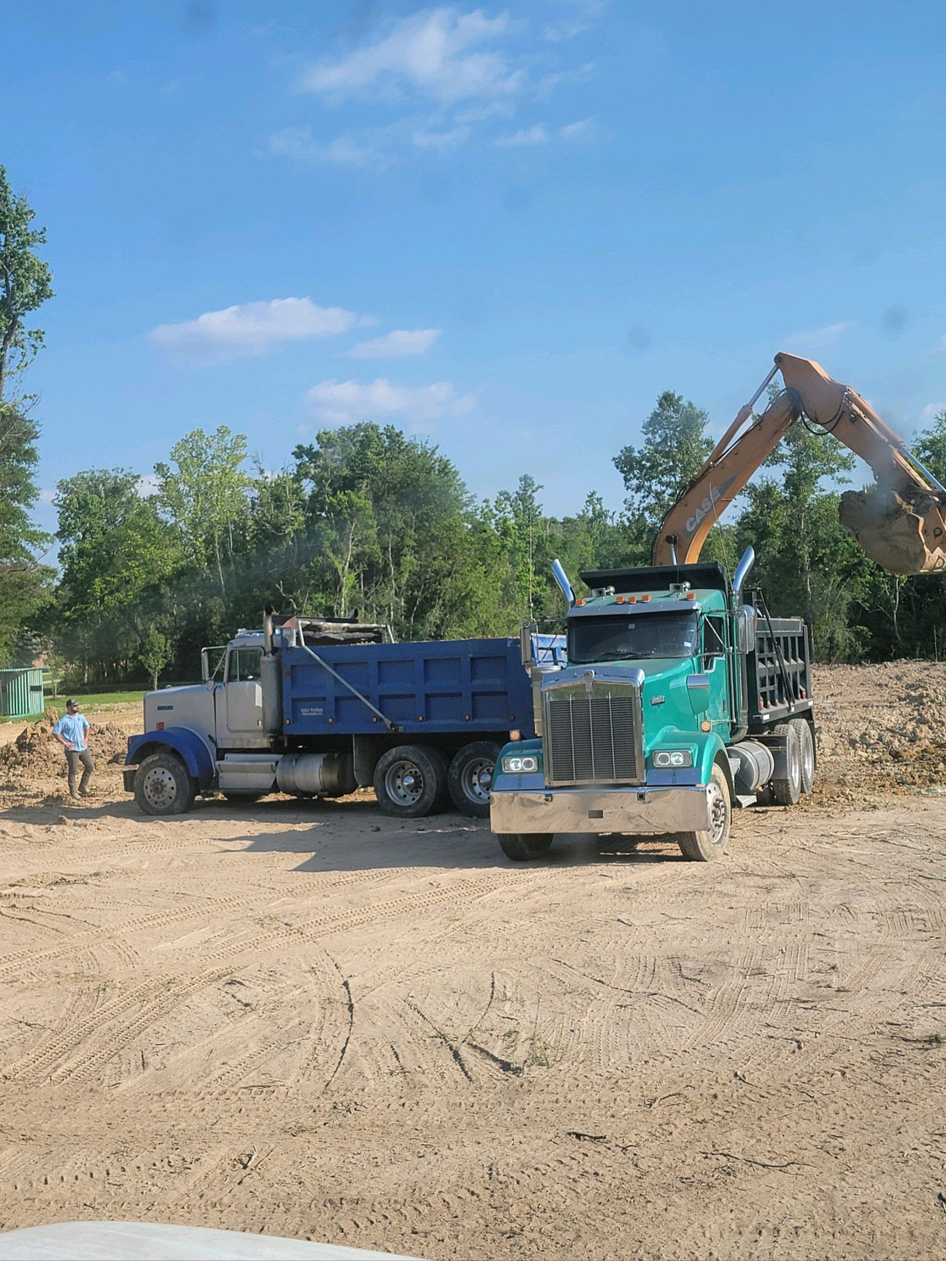 A dump truck and an excavator are parked in a dirt field