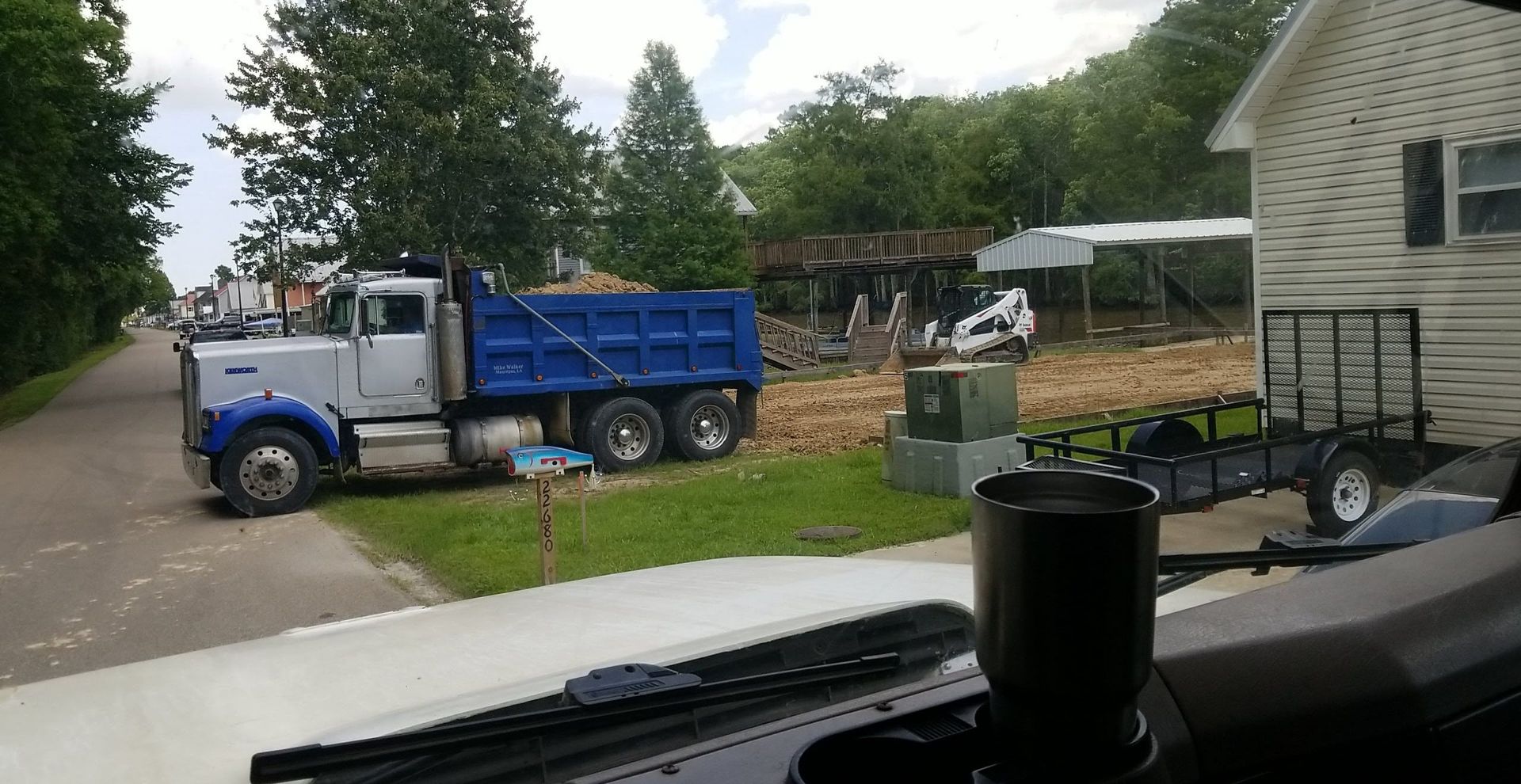 A dump truck is parked on the side of the road next to a house.