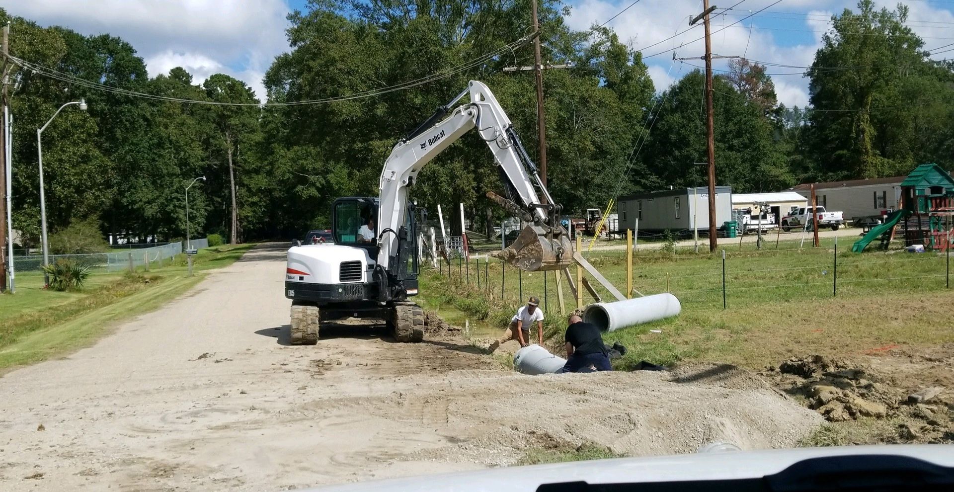 A bulldozer is digging a hole in the dirt next to a road.
