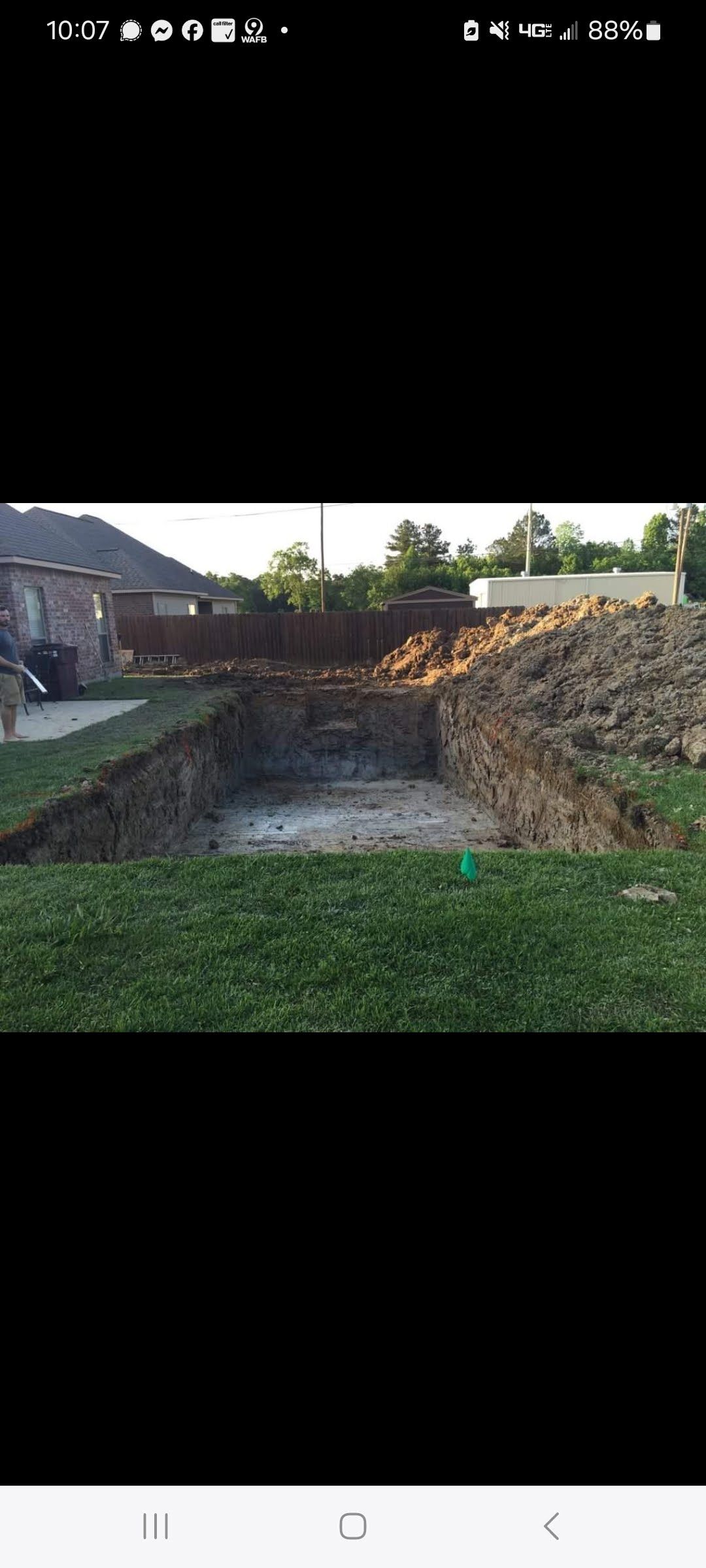 A swimming pool is being built in the backyard of a house.