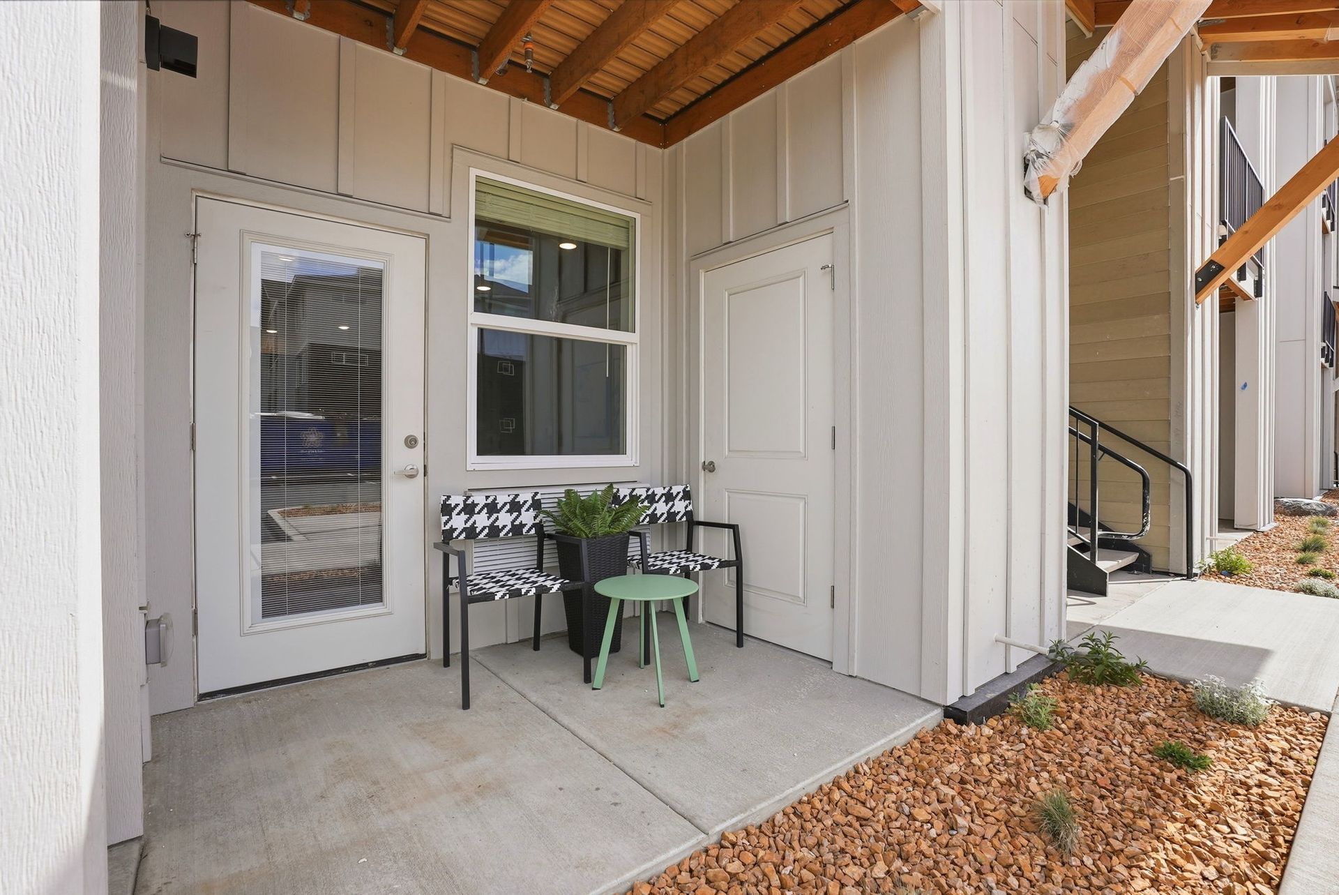 A small patio featuring a wooden bench and a door, surrounded by greenery at The Mill at Ochoco.