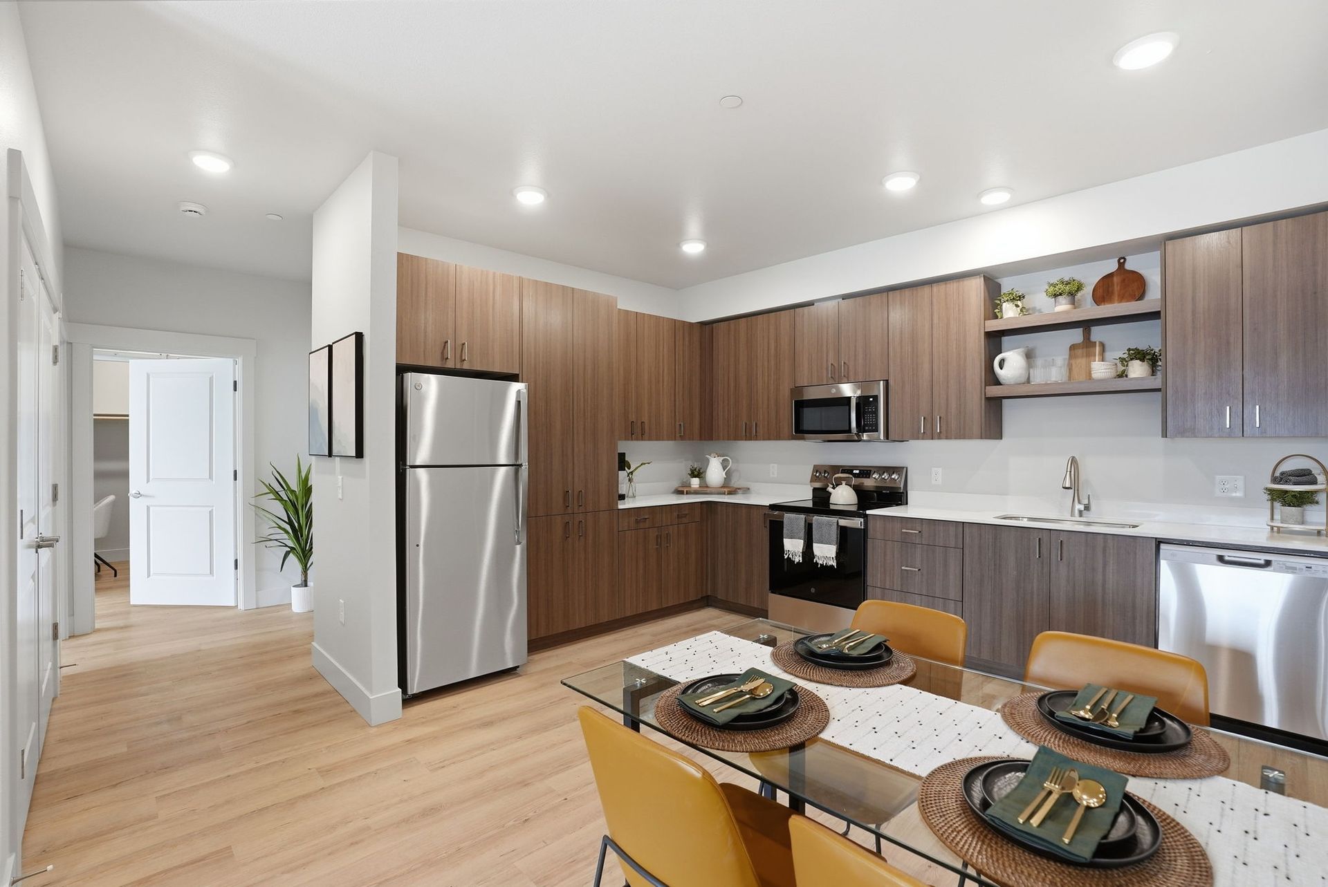 Modern kitchen with stainless appliances, wood cabinets, and a dining table set for four